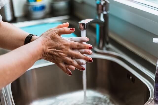 Hands washing under a kitchen sink