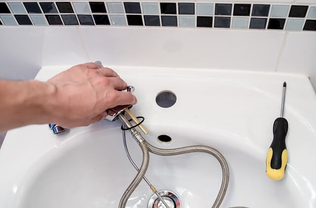 a plumber's hand fixing a bathroom faucet