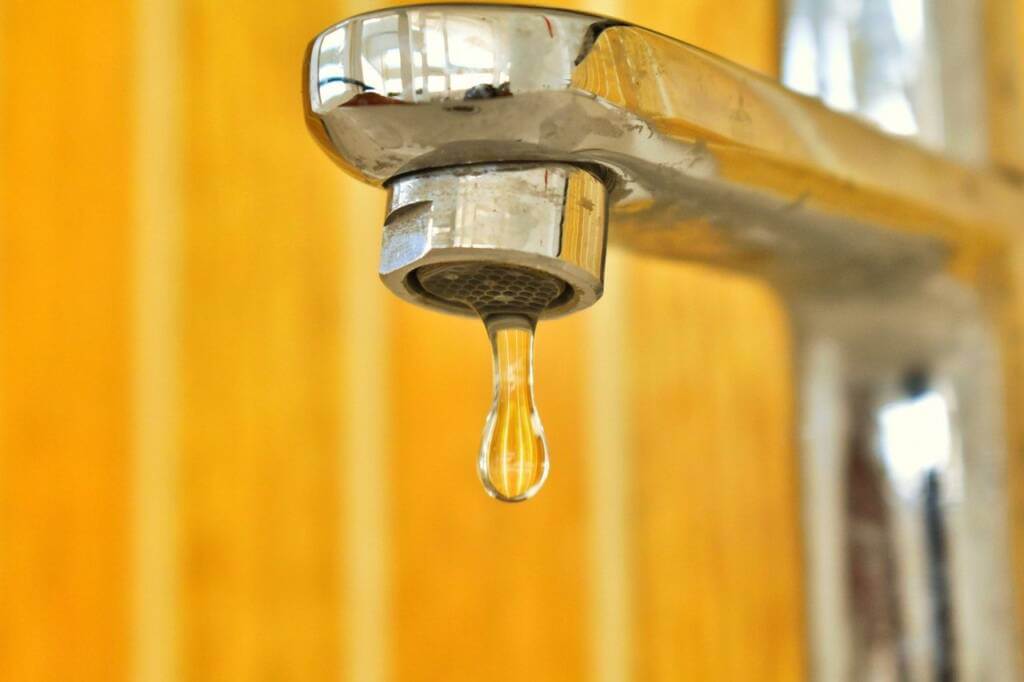 One drip of hot water coming out of a faucet