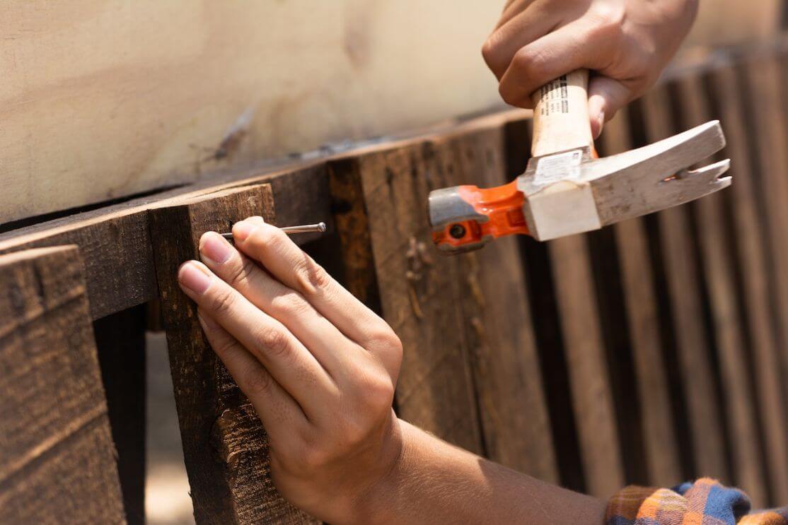 Hand hammering nail against wood