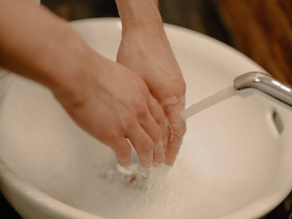 Hands rinsing off in sink water