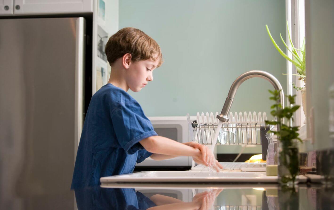 Boy washing his hands under a kitchen tap