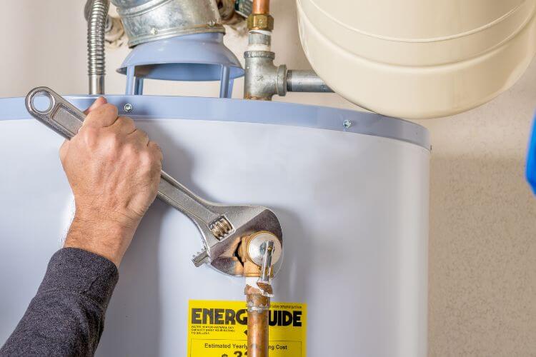 man fixing hot water system with a wrench